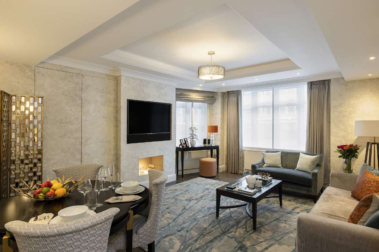An open living and dining room with a fireplace, a wall-mounted television and a table set for dinner
